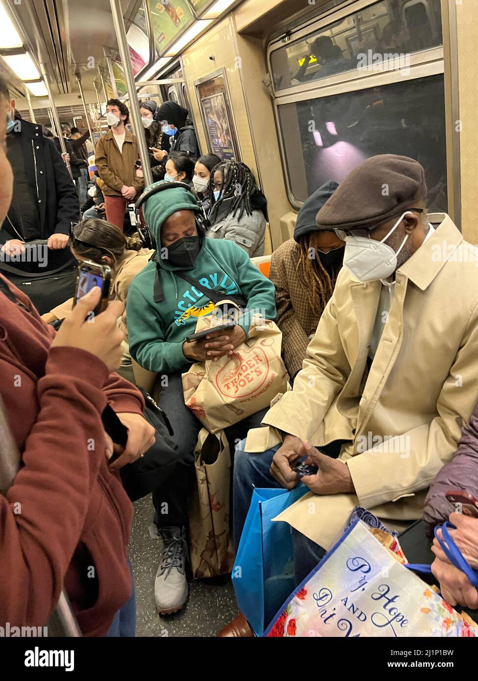 Die U-Bahn-Züge in New York City sind während der Hauptverkehrszeit wieder voll, wo es keine soziale Distanzierung mehr gibt. Im Frühjahr 2022 müssen die Fahrer immer noch Gesichtsmasken tragen. Stockfoto