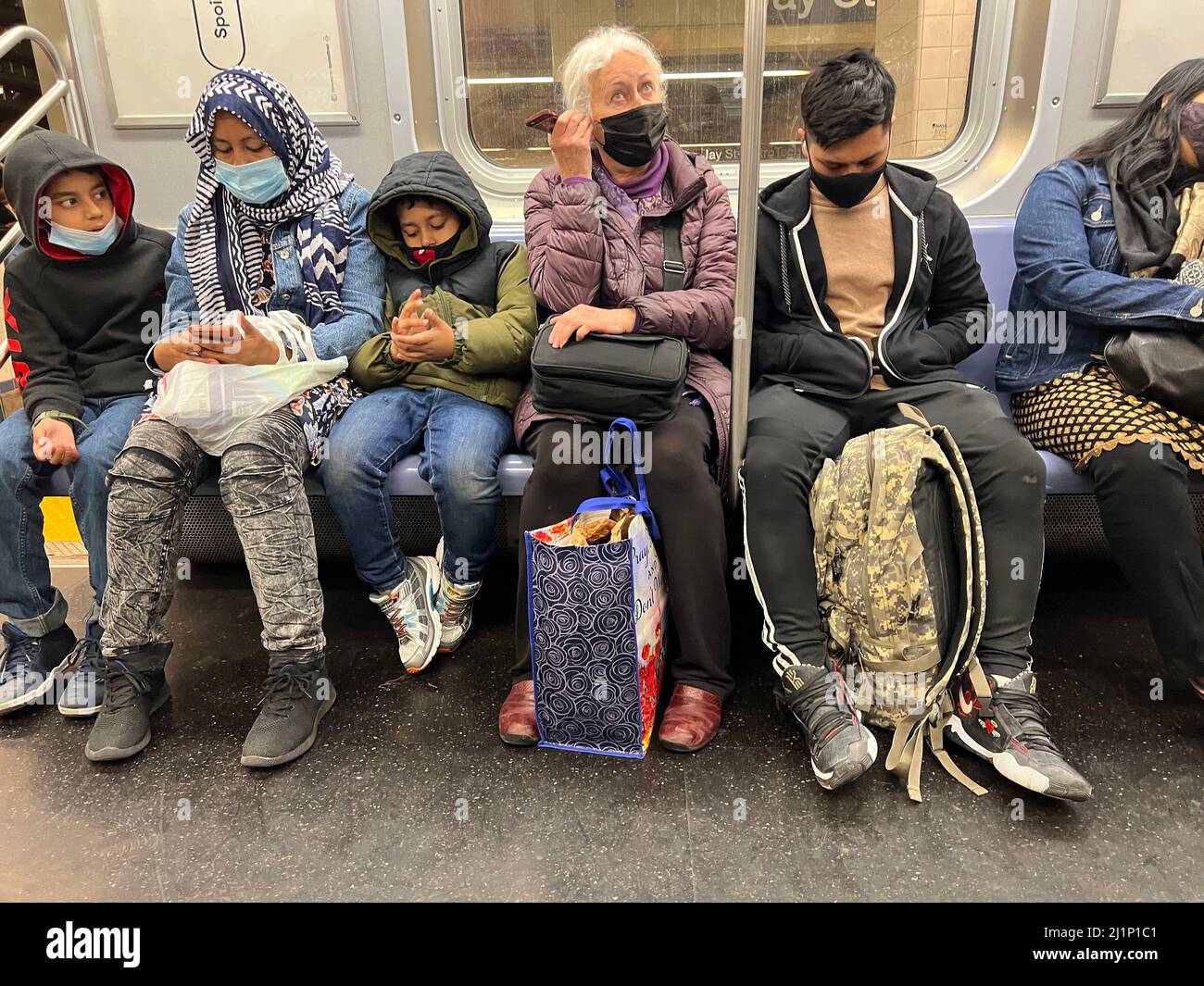 Die U-Bahn-Züge in New York City sind während der Hauptverkehrszeit wieder voll, wo es keine soziale Distanzierung mehr gibt. Im Frühjahr 2022 müssen die Fahrer immer noch Gesichtsmasken tragen. Stockfoto