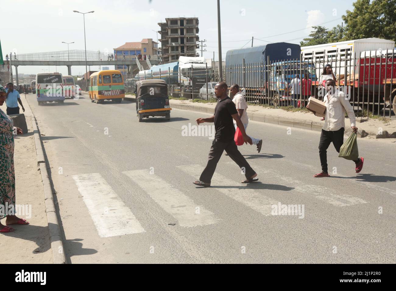 Menschen, die die Mandela Road im Buguruni-Gebiet von dar es Salaam überqueren. FOTO VON MICHAEL MATEMANGA Stockfoto