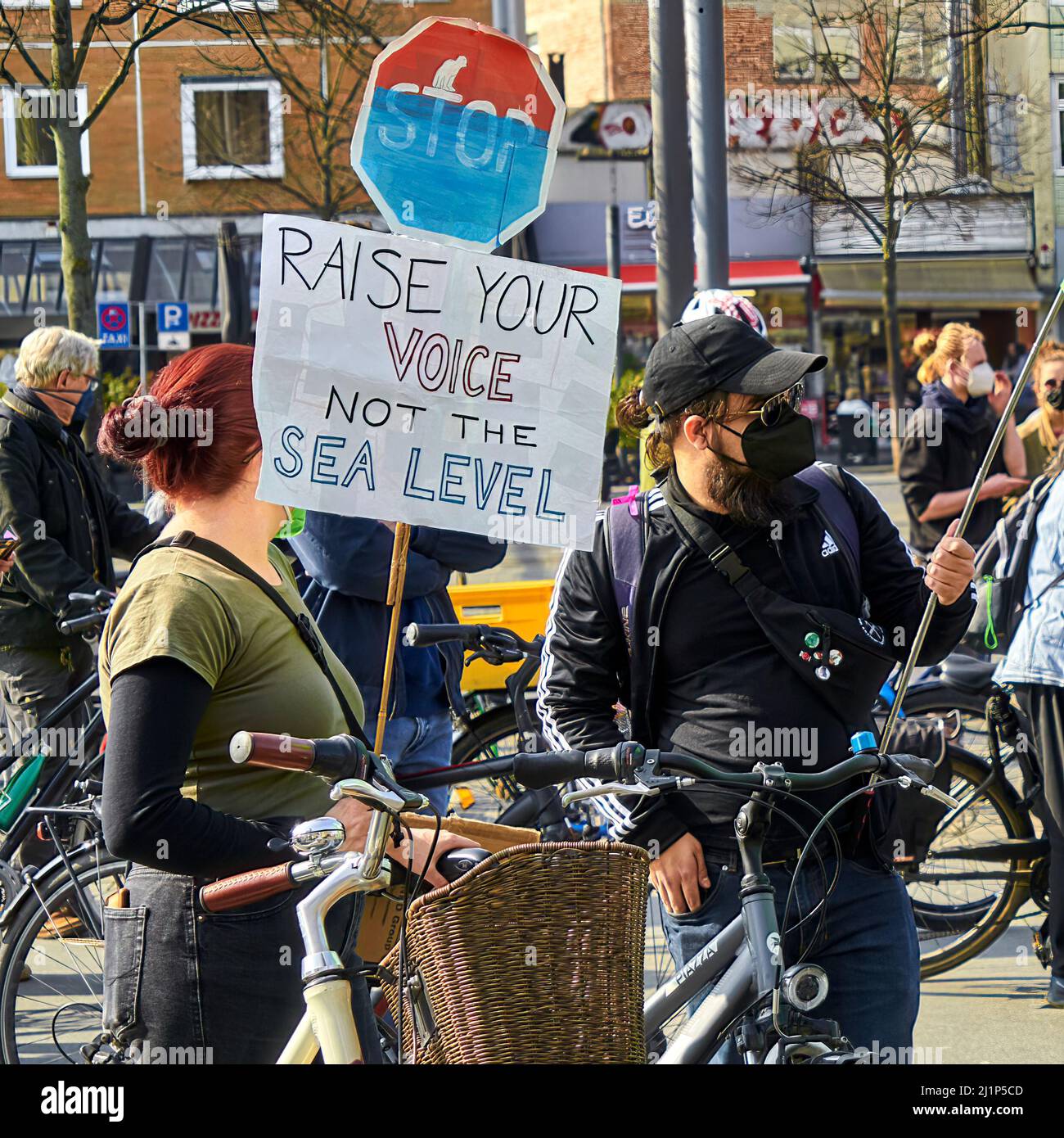 Braunschweig, 25. März 2022: Rotschopf-Frau und -Mann in dunkler Kleidung mit Fahrrad auf Demonstration für den globalen Klimastreik 2022 Stockfoto