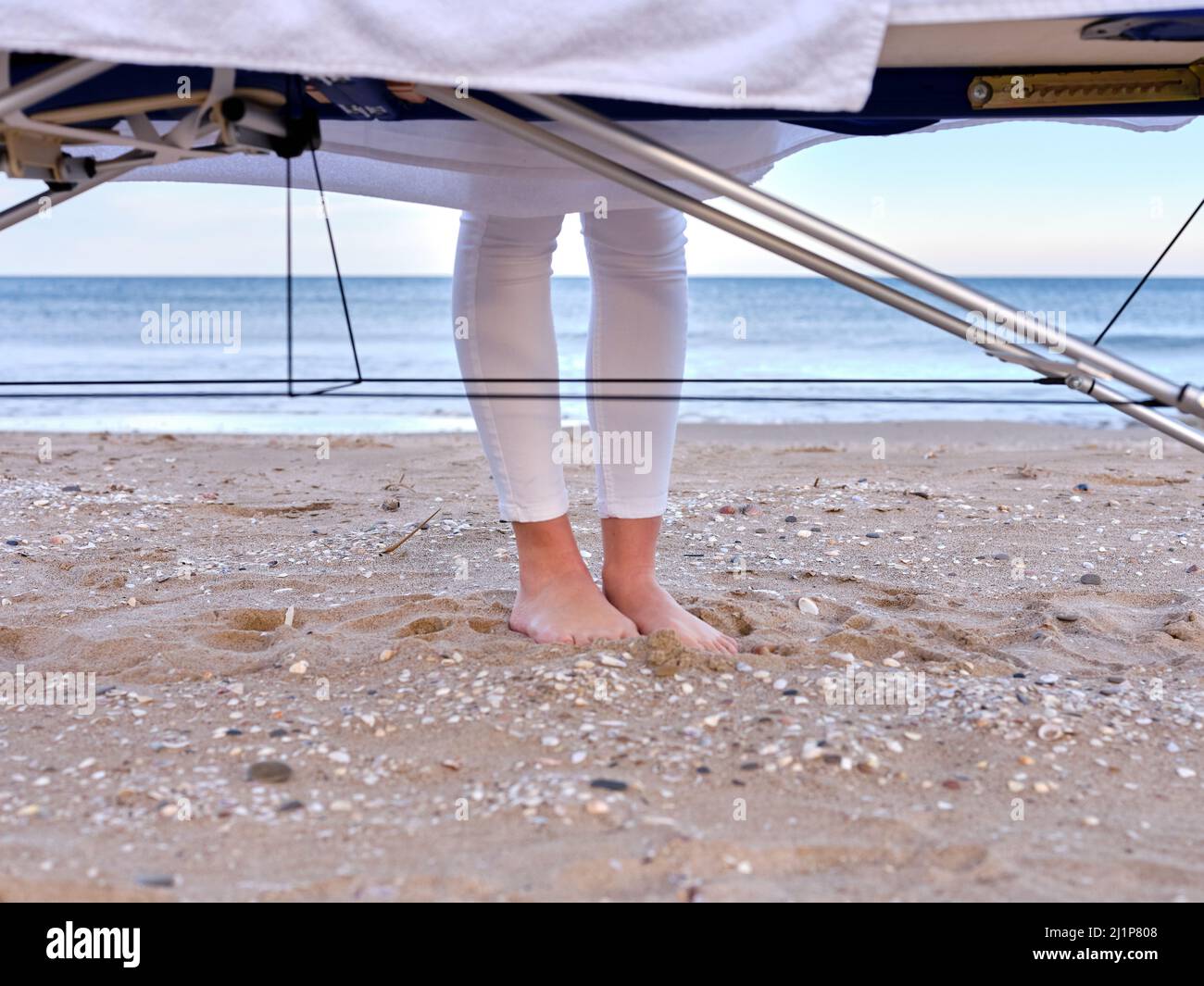 Blick auf die Füße eines jungen Chiromassage-Therapeuten und den Massageliege an einem Strand in Valencia, Spanien. Stockfoto
