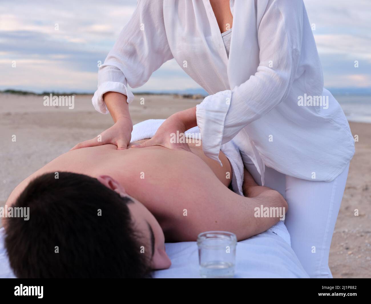 Ein junger Mann, der eine Chiromassage-Behandlung durch einen Chiromassage-Therapeuten an einem Strand in Valencia erhält. Stockfoto