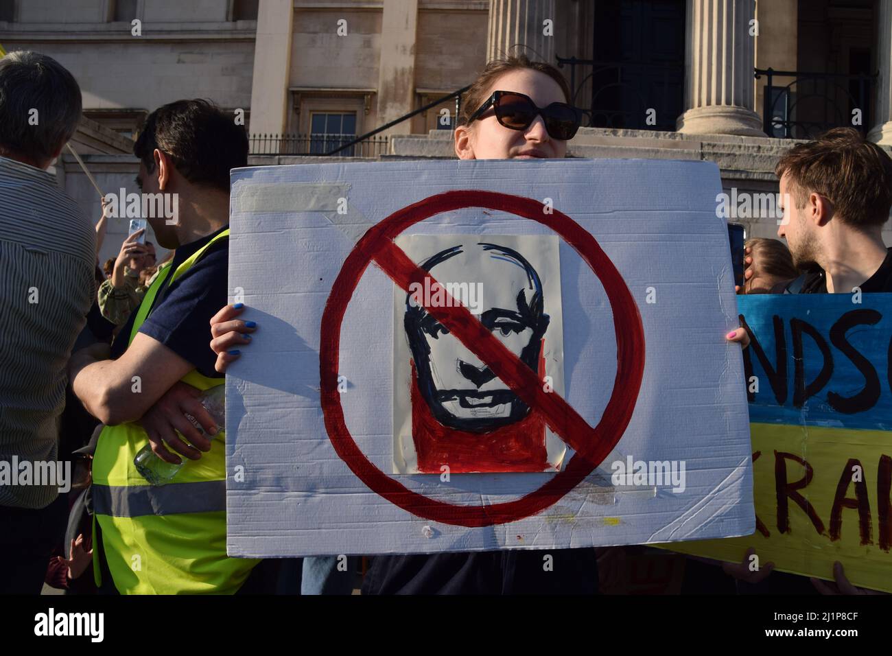 Ein Protestler hält während der Kundgebung „London steht mit der Ukraine“ auf dem Trafalgar Square ein Plakat gegen Wladimir Putin. Tausende von Menschen marschierten aus Solidarität mit der Ukraine von der Park Lane zum Trafalgar Square, während Russland seinen Angriff fortsetzt. Stockfoto