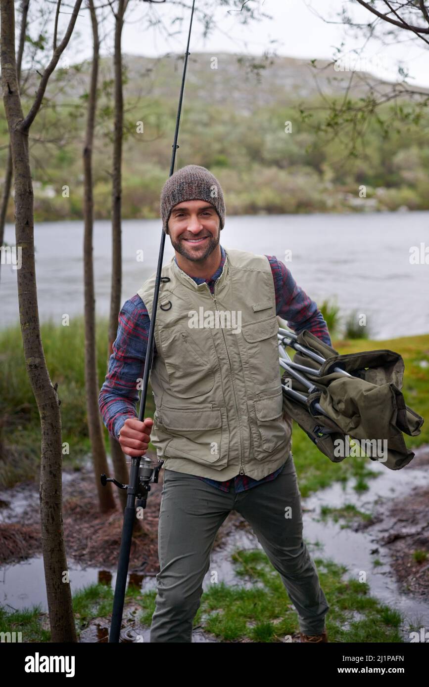 Angeln - seine Idee des Spaßes. Porträt eines hübschen jungen Mannes, der seine Angeltour genießt. Stockfoto