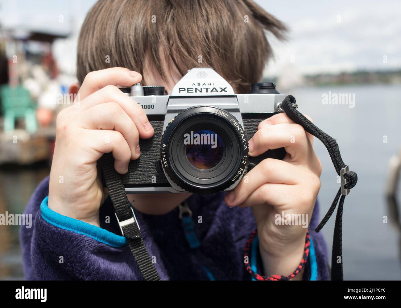 Ein kleiner Junge versucht zu lernen und mit der Filmkamera zu fotografieren. Junge mit Filmkamera Fotografie lernen. Pentax Filmkamera und ein Kind. Talentiertes Kind. Stockfoto
