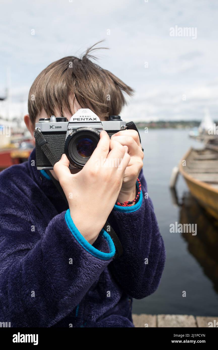 Junge lernt und fotografiert mit der Filmkamera. Junge mit Filmkamera Fotografie lernen. Pentax Filmkamera und ein Kind. Kind, das sich auf die Aufgabe konzentriert. Stockfoto