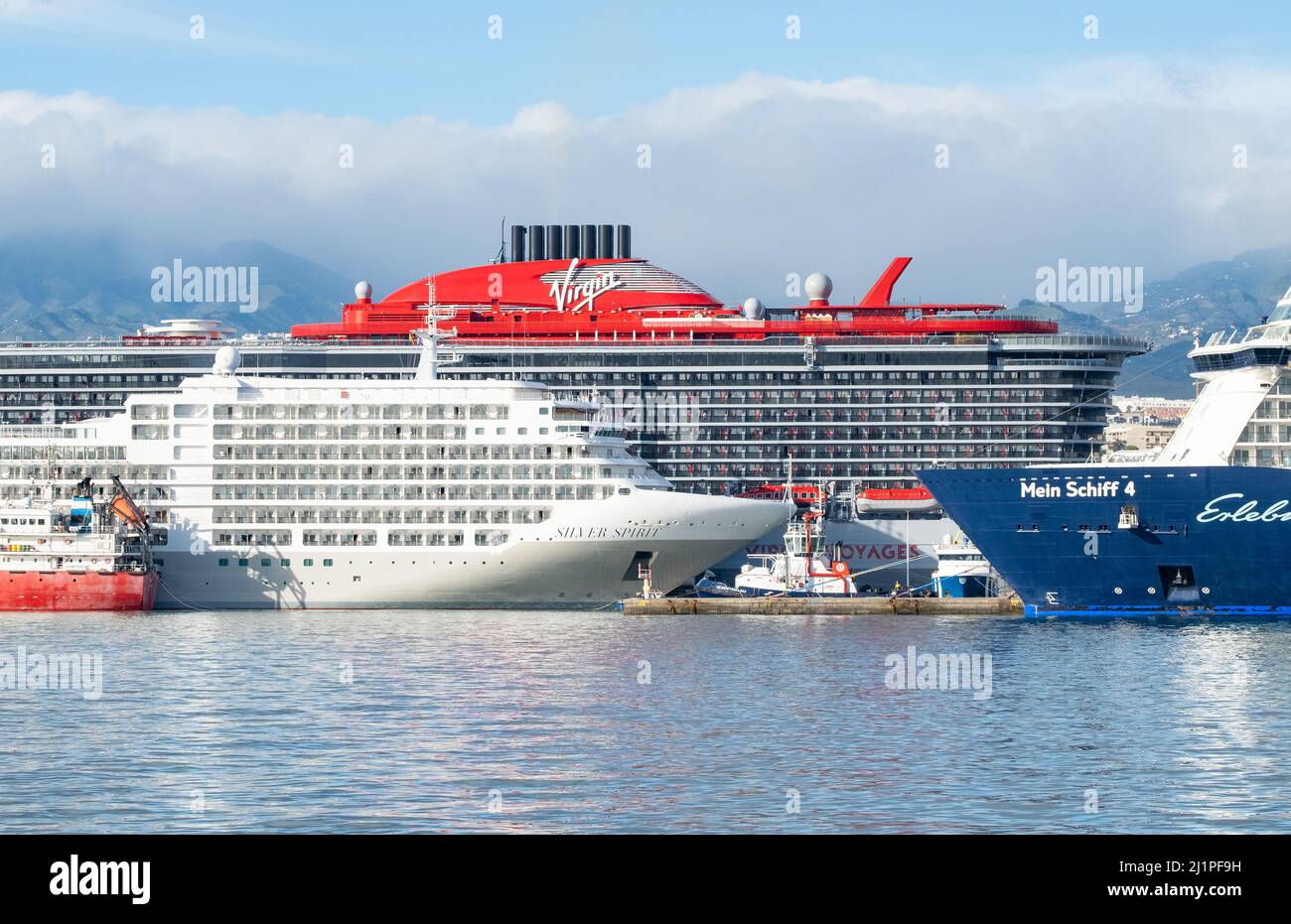 Las Palmas, Gran Canaria, Kanarische Inseln, Spanien. 27.. März 2022. Das Virgin Voyages-Kreuzschiff Valiant Lady überragt auf seiner ersten Kanarischen Kreuzfahrt andere Kreuzschiffe in Las Palmas auf Gran Canaria. Unter den 80s Stars, die an Bord auftreten, sind Martin Fry von ABC, Tony Hadley vom Spandau Ballet, Toya... Kredit: Alan Dawson/ Alamy Live Nachrichten. Stockfoto