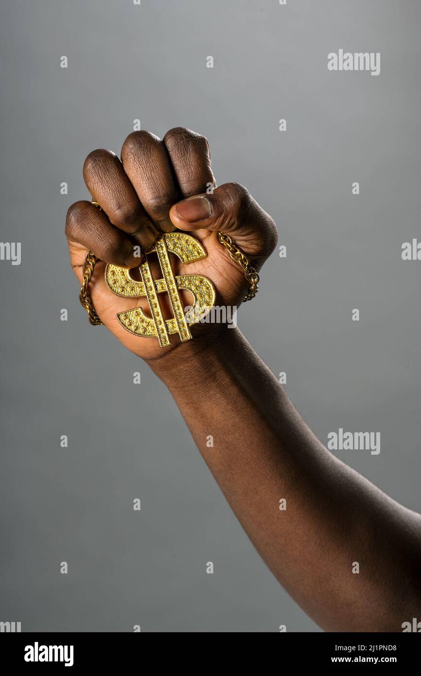 Crop unkenntlich afroamerikanischen Mann hält goldene Halskette mit Dollar-Symbol auf grauem Hintergrund Stockfoto