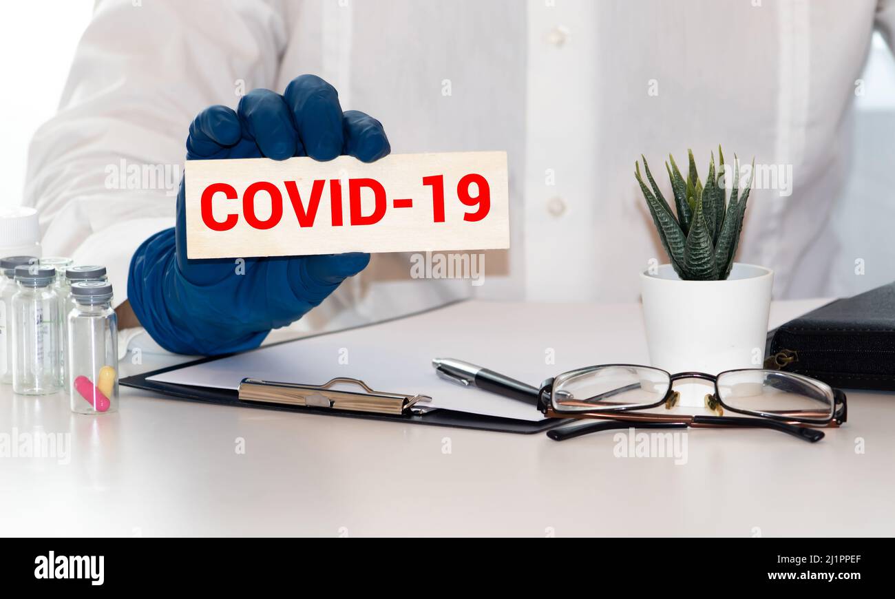 Gesichtsmaske in der Hand mit dem Wort covid-19. Covid 19 Ausbruch auf der ganzen Welt. Die globale Wirtschaftskrise. Absturz durch Coronavirus. Das Leben im Lockdown um Th Stockfoto