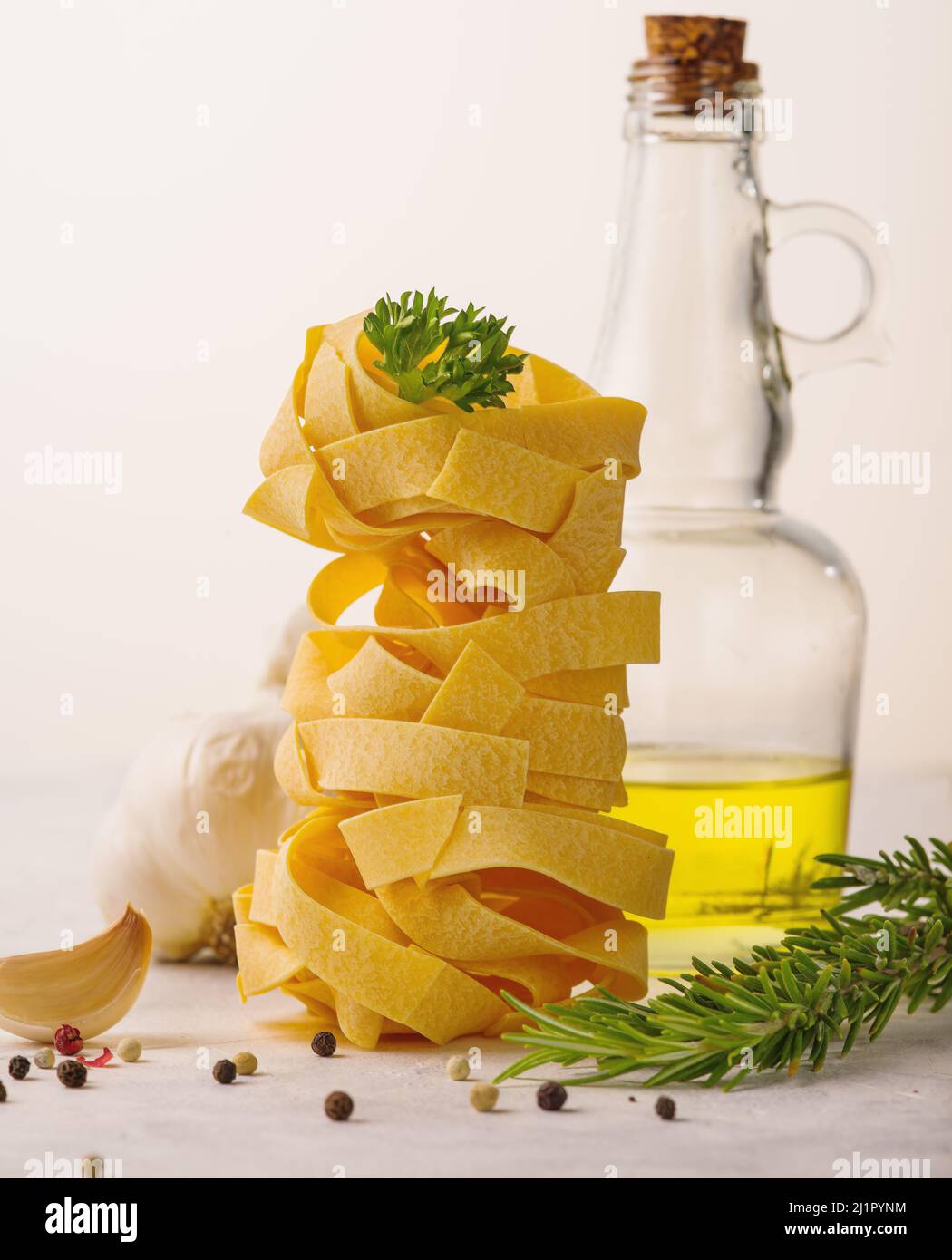 Italienische Pasta in einer vertikalen Portion, Knoblauch, Olivenöl und ein Zweig Rosmarin auf weißem Hintergrund. Nahaufnahme. Kochen, italienisches Essen. Gesunde Lebensmut Stockfoto