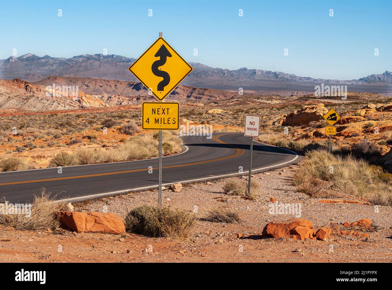 Overton, Nevada, USA - 11. Dezember 2010: Valley of Fire. Schwarze Asphaltstraße schlängelt sich durch breite braune Gebirgswüste Landschaft mit gelb scharfen t Stockfoto