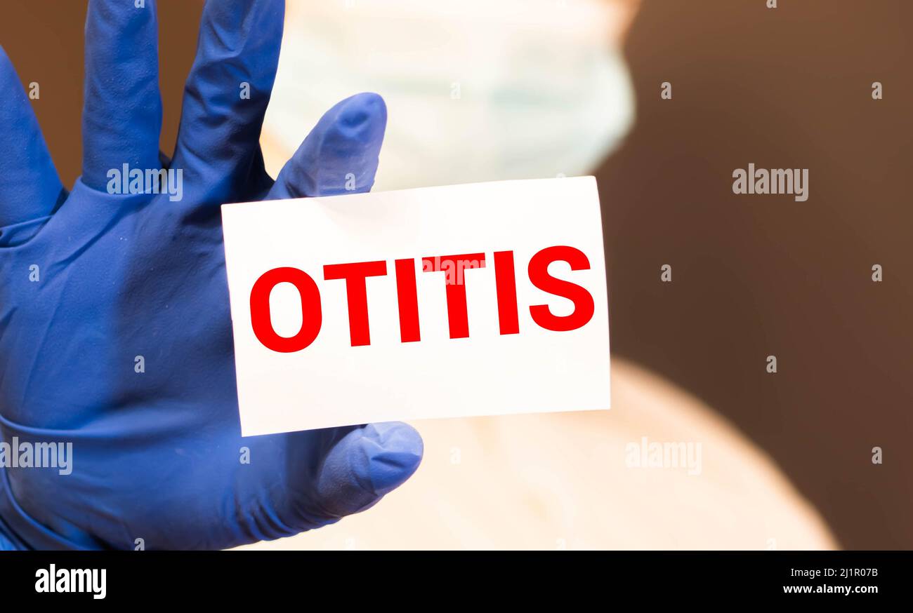Die Hände des Arztes in blauen Handschuhen zeigen das Wort Otitis. Medizinisches Konzept Stockfoto