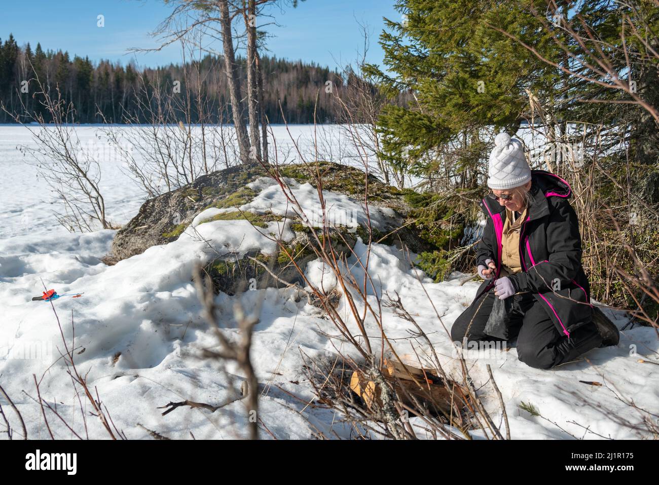 Ältere Frauen, die während einer Pause vom Winterfischen ein Lagerfeuer am Ufer machen, Bild aus Mellansel vasternorrland schweden. Fokus auf Vordergrund. Stockfoto