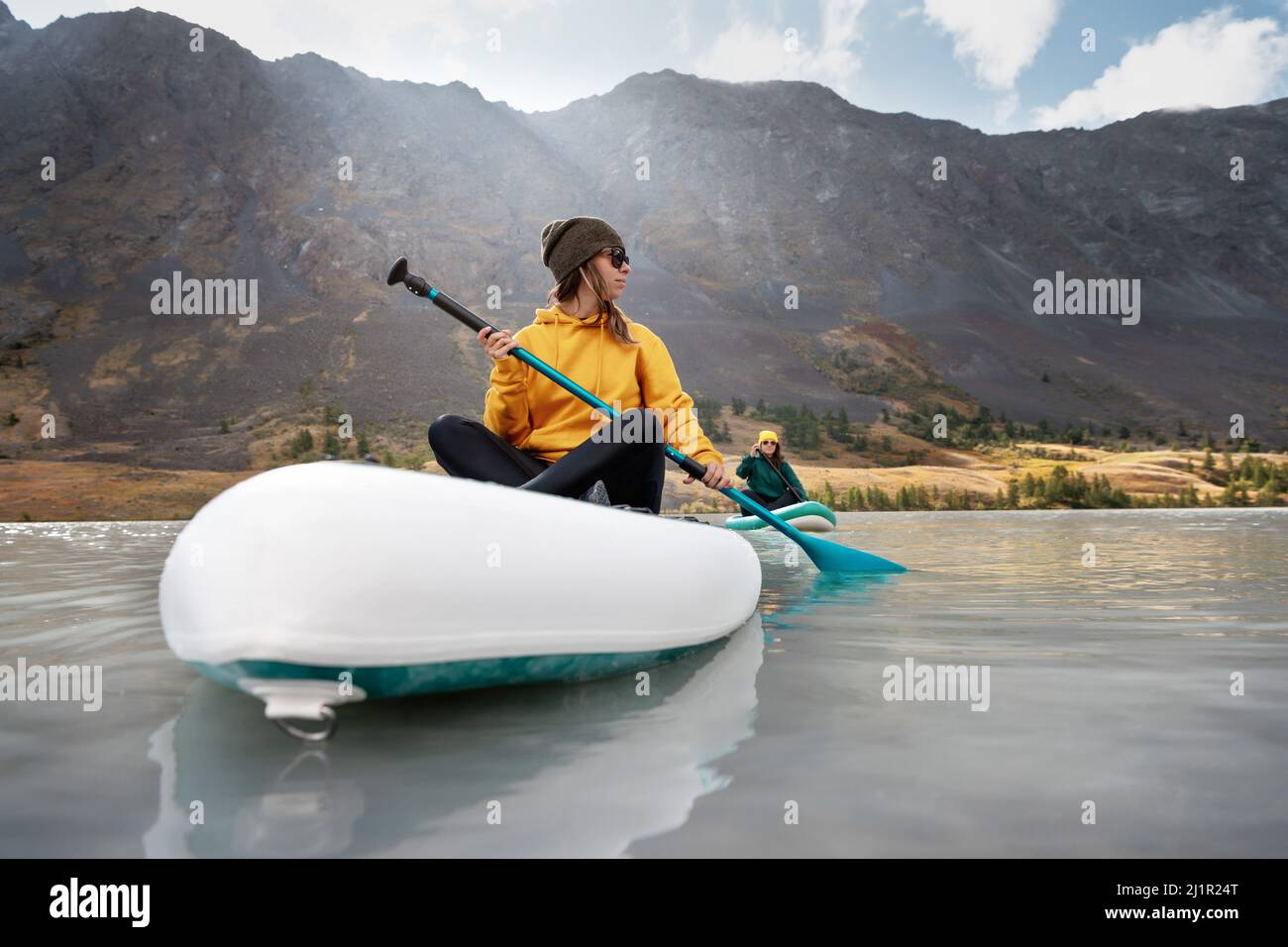 Zwei junge Mädchen gehen auf Stand Up Paddle Boards am Bergsee Stockfoto