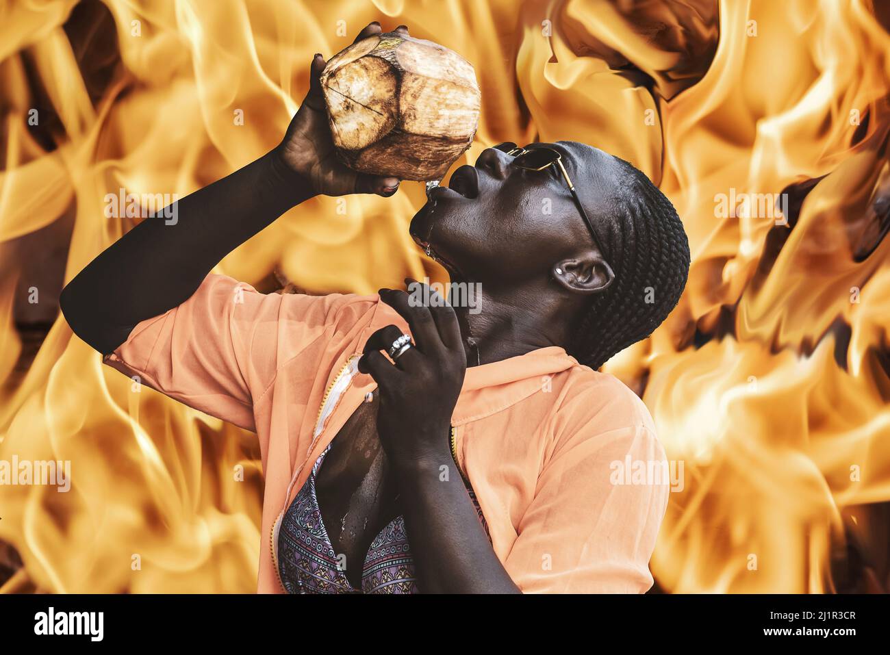 Die Afrikanerin kühlt sich in der Hitze mit einer Kokosnuss ab, einem Feuer, das die Hitze in Afrika veranschaulicht Stockfoto