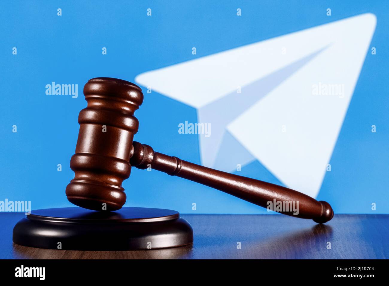 Gavel auf dem Tisch vor dem Hintergrund des Telegram Messenger Logos. Das Konzept des Trials. Stockfoto