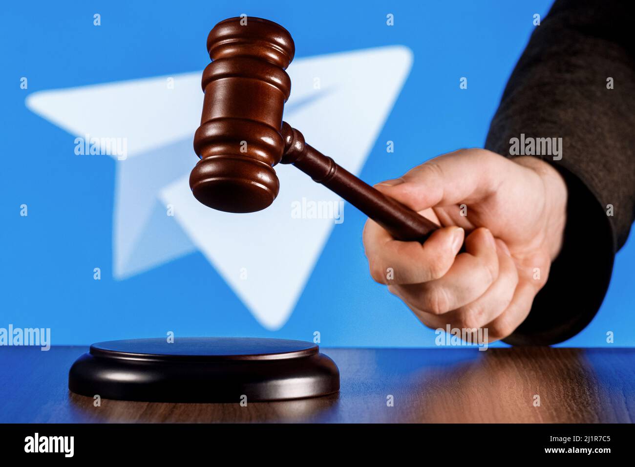 Gavel in Richterhand vor Hintergrund des Telegram Messenger Logos. Das Konzept des Trials. Stockfoto