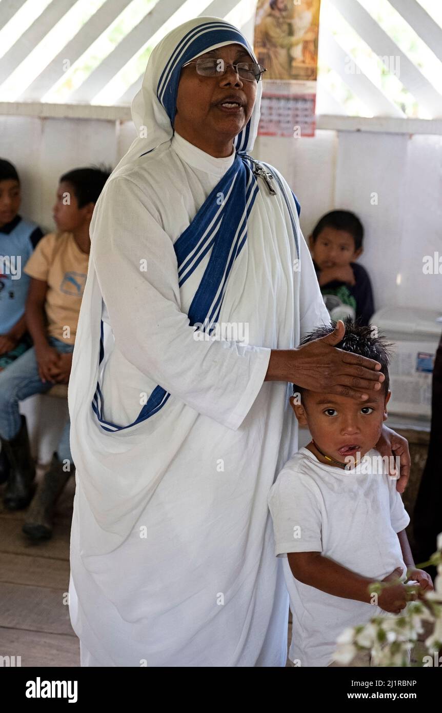 Mutter Teresa Schwester, die in Costa Rica über einen indigenen Jungen betet Stockfoto