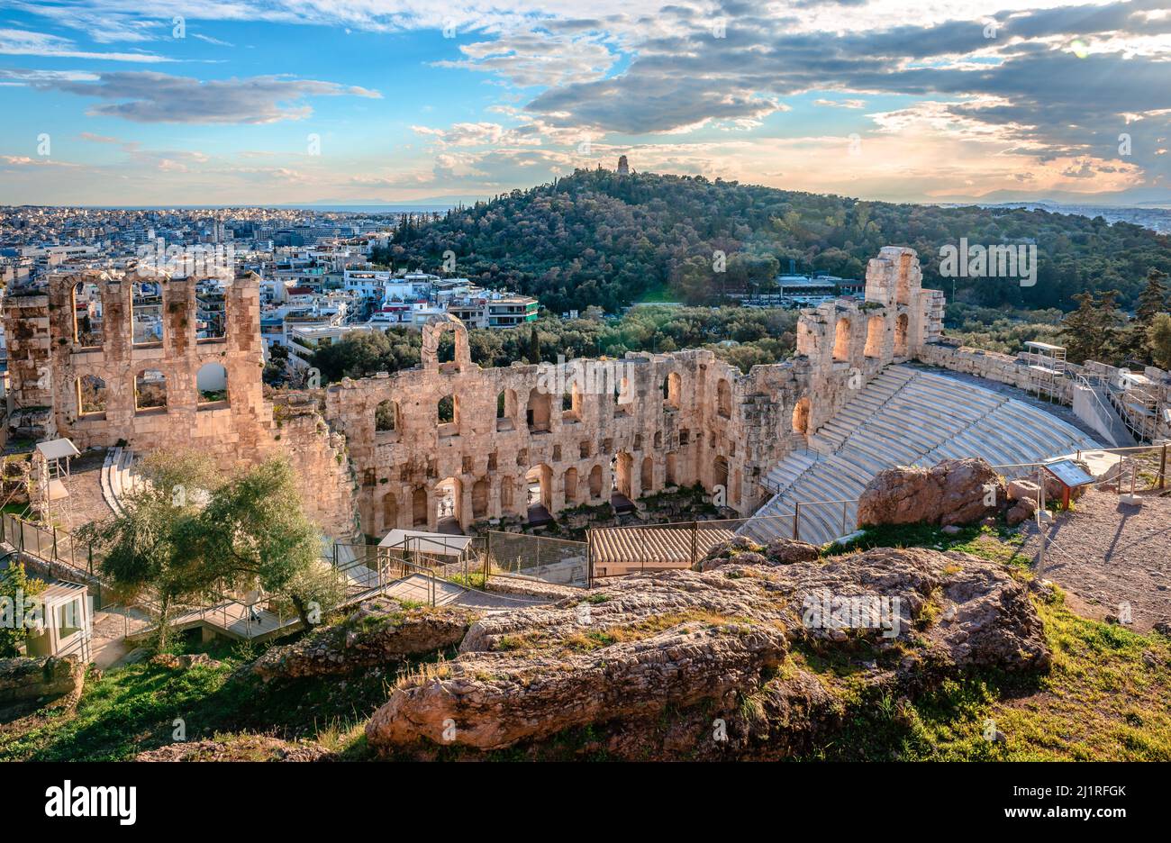 Sonnenuntergang über dem Odeon des Herodes Atticus, gelegen am Südwesthang der Akropolis, in Athen, Griechenland. Filopappos Hill mit dem Filopappos monu Stockfoto