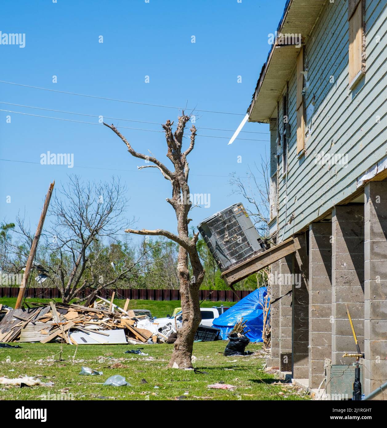 ARABI, LA, USA - 26. MÄRZ 2022: Stark beschädigte Klimaanlage an der Seite des Hauses und Baumreste, die bis zum Tornado vom 22. März abgestreift wurden Stockfoto