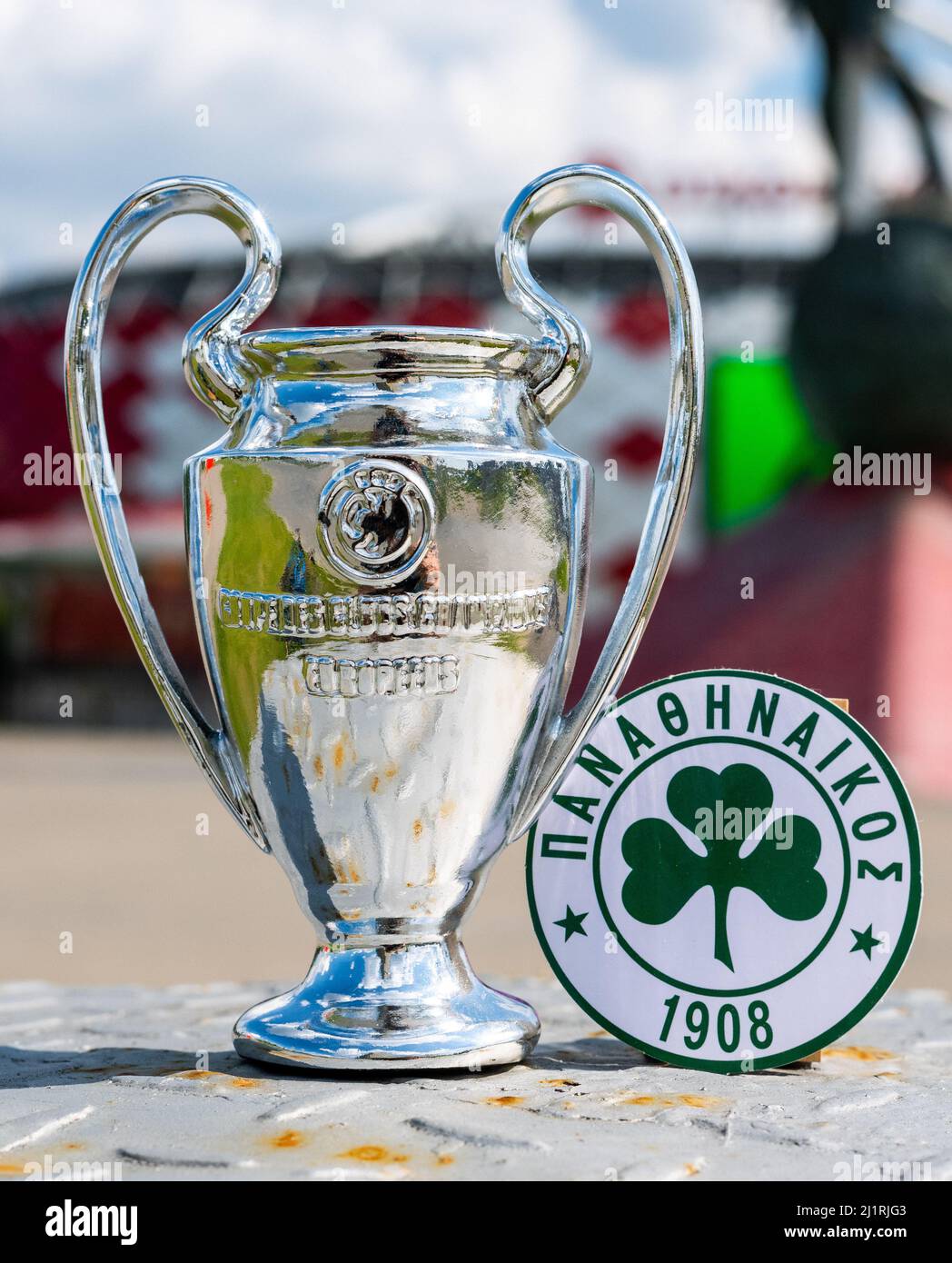 14. Juni 2021 Athen, Griechenland. Das Emblem des Fußballvereins Panathinaikos F. C. und des UEFA Champions League Cup auf dem Hintergrund einer modernen Stadt Stockfoto