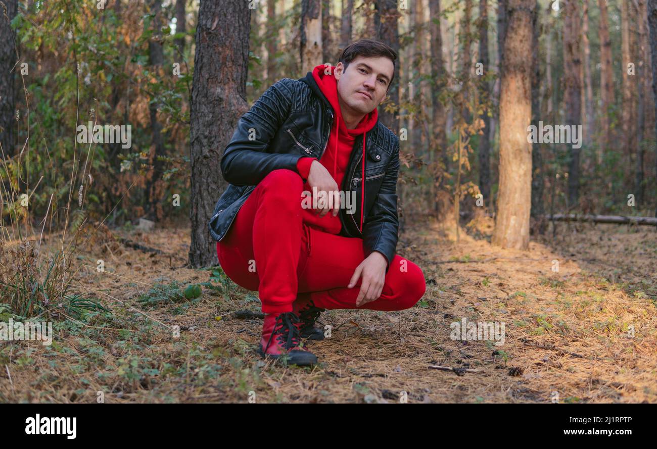 Ein junger, hübscher Mann posiert im Herbstwald bei Sonnenuntergang. Stockfoto