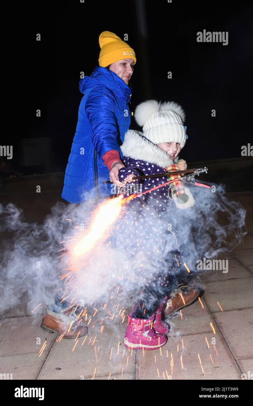 Vendrell, Spanien. 5. Januar 2022. Eine ukrainische Flüchtlingsmutter mit ihrer Tochter spielt mit einem Feuerwerkskörper in Vendrell. Der Verein ''DRAC de FOC El Cabrot de El Vendrell'' (Feuerdrache) handelt in einer pyrotechnischen Darstellung in Solidarität und Unterstützung für Menschen ukrainischer Nationalität, die aufgrund der Invasion Russlands in der Ukraine in Hotels und kommunalen Hostels in der Stadt Vendrell Flüchtlinge sind, Die Aufführung von Feuerparaden ist eine katalanische Tradition, die jedes Jahr in Städten und Gemeinden stattfindet. (Bild: © Ramon Costa/SOPA Images via ZUMA Press Wire) Stockfoto