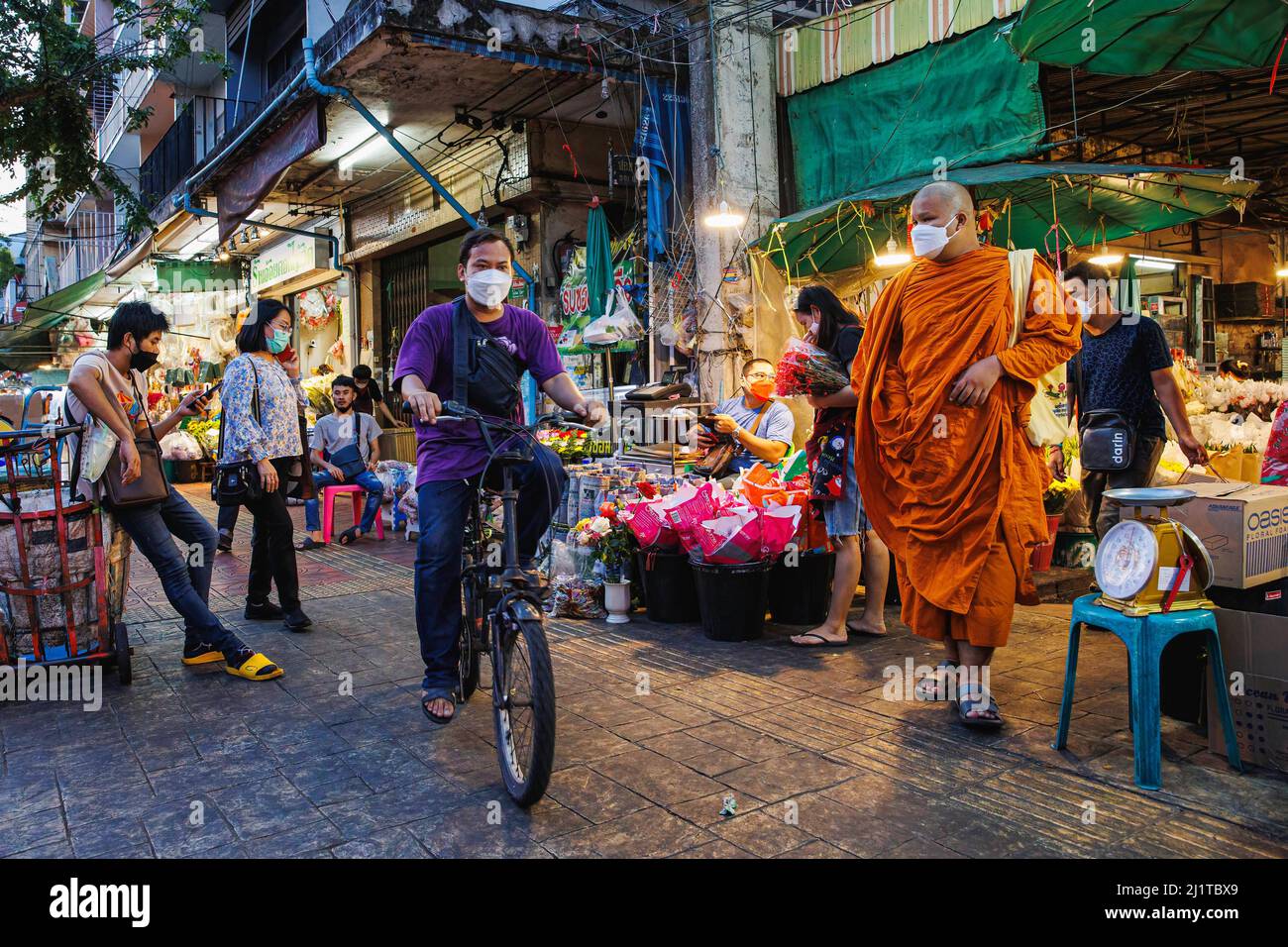 Bangkok, Thailand. 17. März 2022. Ein Radfahrer fährt an einem Mönch vor dem Blumengeschäft auf dem Pak Klong Talat Blumenmarkt vorbei. Rattanakosin Island, das Innere Bangkoks, ist der Kern der historischen und kulturellen Zone Bangkoks. Dieser Ort ist auch bekannt als eine alte Stadt wegen des Alters der Zone, dass mehr als 100 Jahre des Bestehens. Nicht nur Palast, Tempel und Wahrzeichen dieser Zone umfassen das Leben und die Aktivitäten der Menschen, die rund um die heilige Gegend von Bangkok leben. (Foto von Varuth Pongsapipatt/SOPA Images/Sipa USA) Quelle: SIPA USA/Alamy Live News Stockfoto