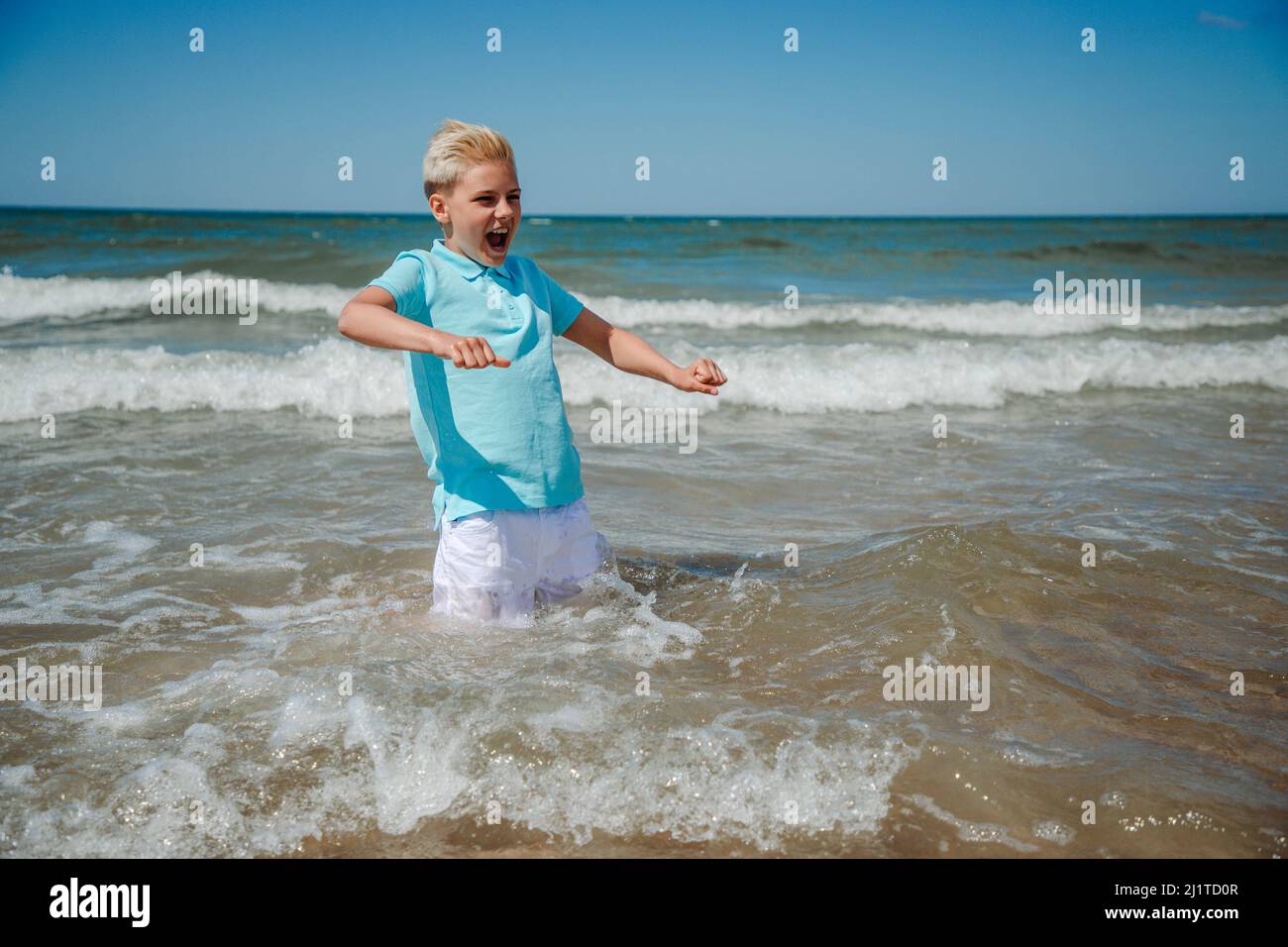 Teenager Junge planscht im Meer Stockfoto