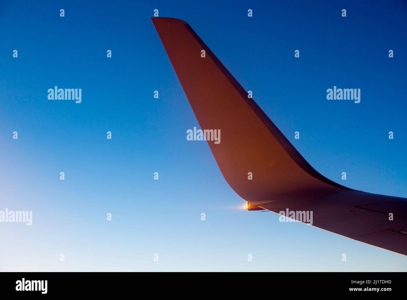 Eine erhöhte rote Flügelspitze eines Boeing-Düsenflugzeugs, das im späten Nachmittagslicht und bei wolkenlosem Himmel in großer Höhe fliegt Stockfoto