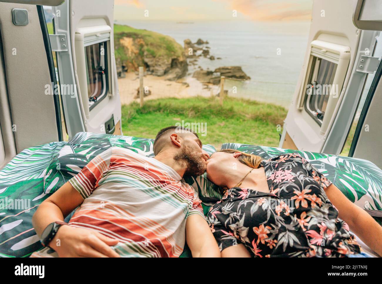Das Paar küsst sich auf dem Bett ihres Wohnwagens Stockfoto