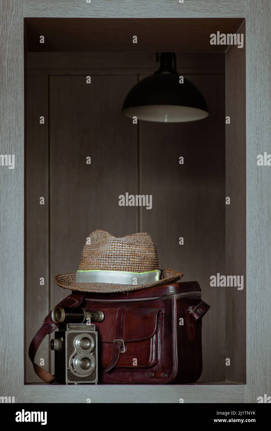 Vintage binokular auf Vintage zwei Linsen Fotokamera Vorderseite Straw Fedora Hut auf Vintage braun Ledertasche in quadratischen Holzrahmen Innenraum. Vintage-Stall Stockfoto