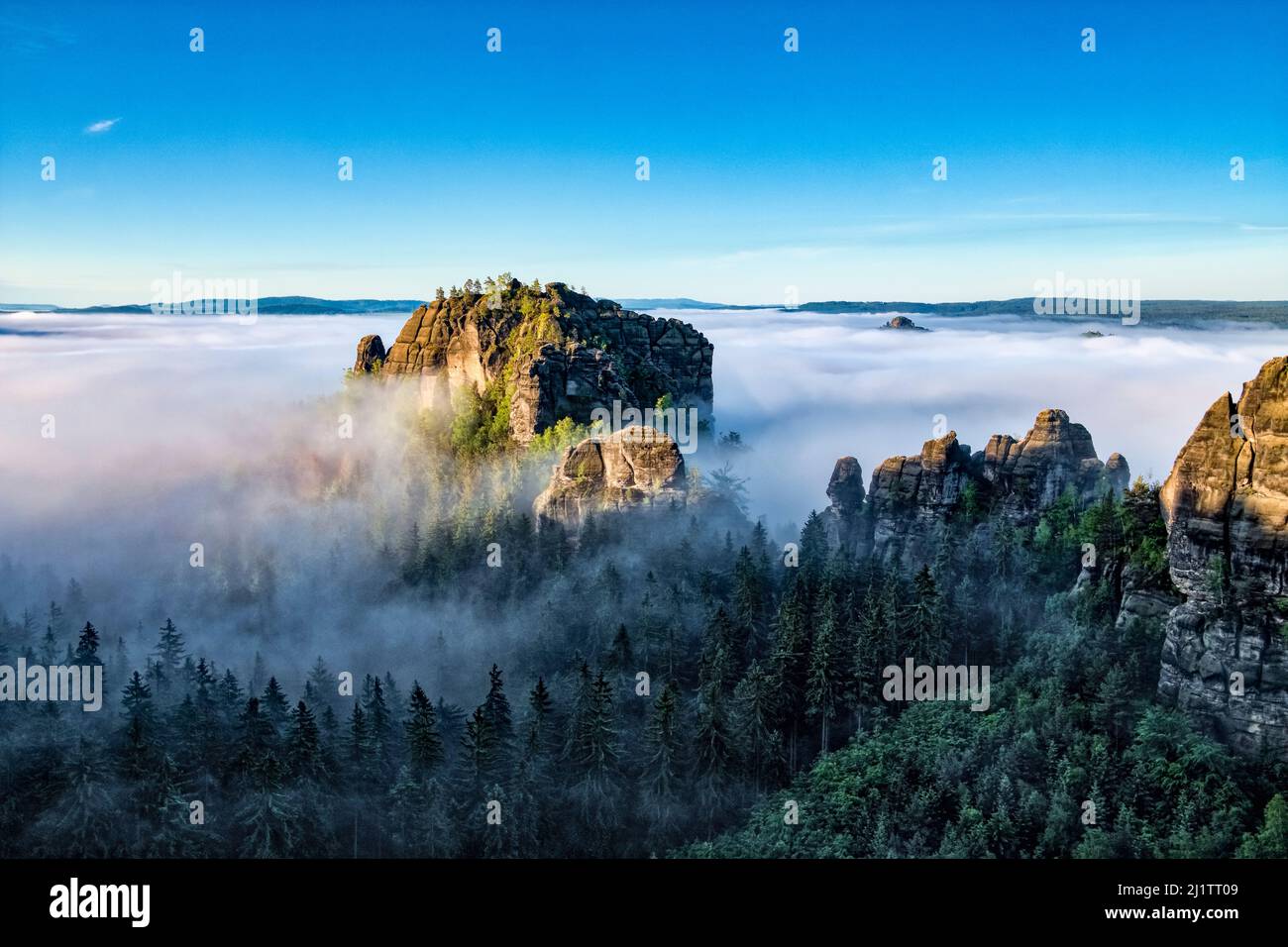 Nebelbedeckte Landschaft mit Felsformationen und der Gipfel Rauschenstein im Schmilka-Gebiet des Nationalparks Sächsische Schweiz bei Sonnenaufgang. Stockfoto