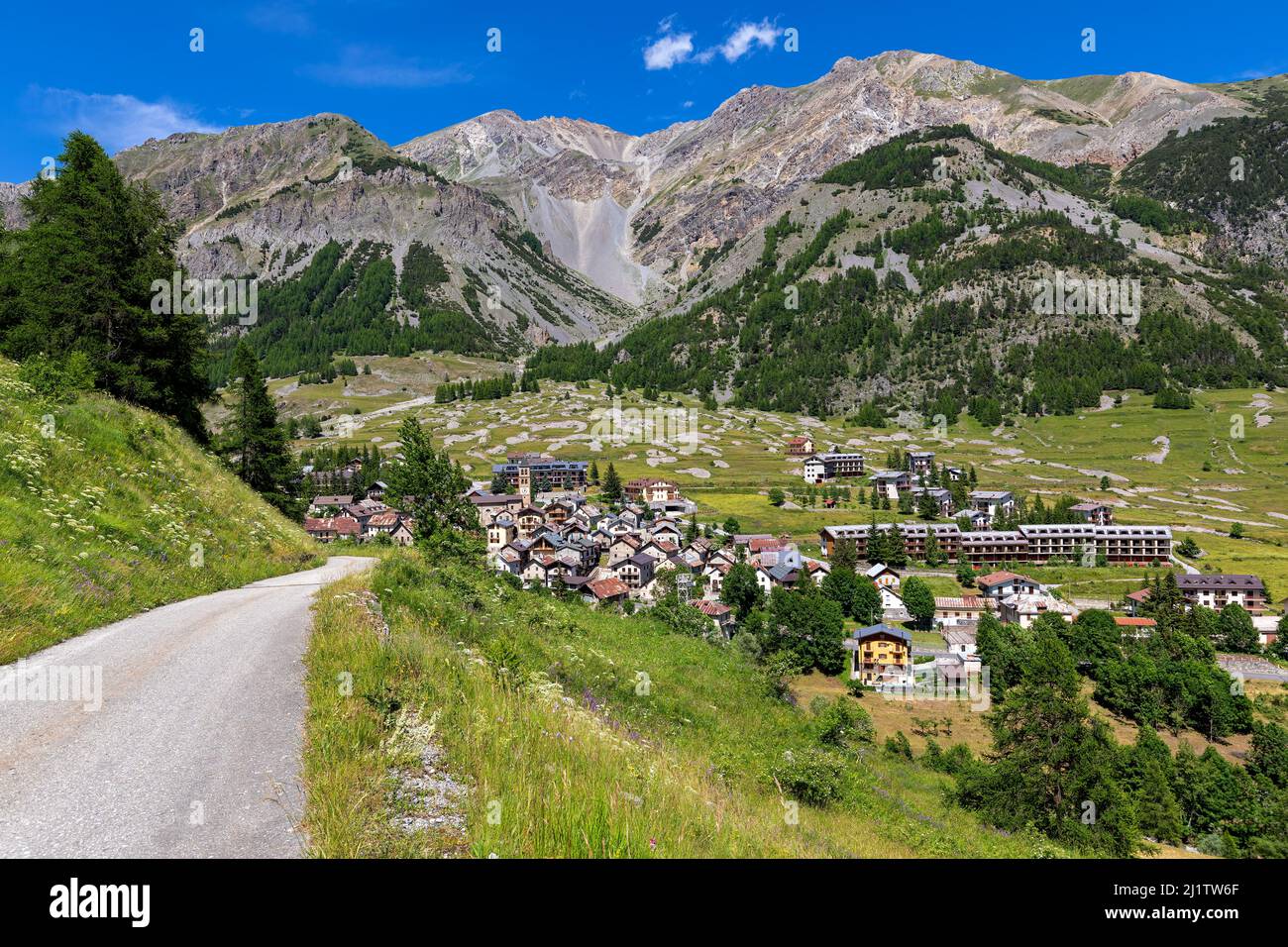 Kleine alpine Stadt Bersezio zwischen grünen Hügeln und Bergen unter blauem Himmel im Piemont, Norditalien. Stockfoto