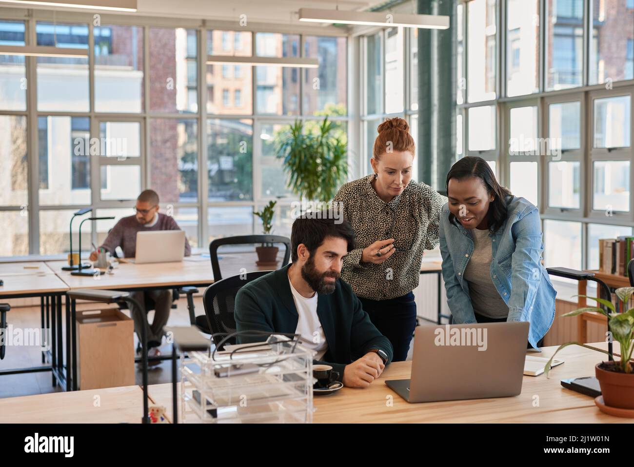 Eine Gruppe von konzentrierten Geschäftsleuten, die an einem Laptop arbeiten Stockfoto