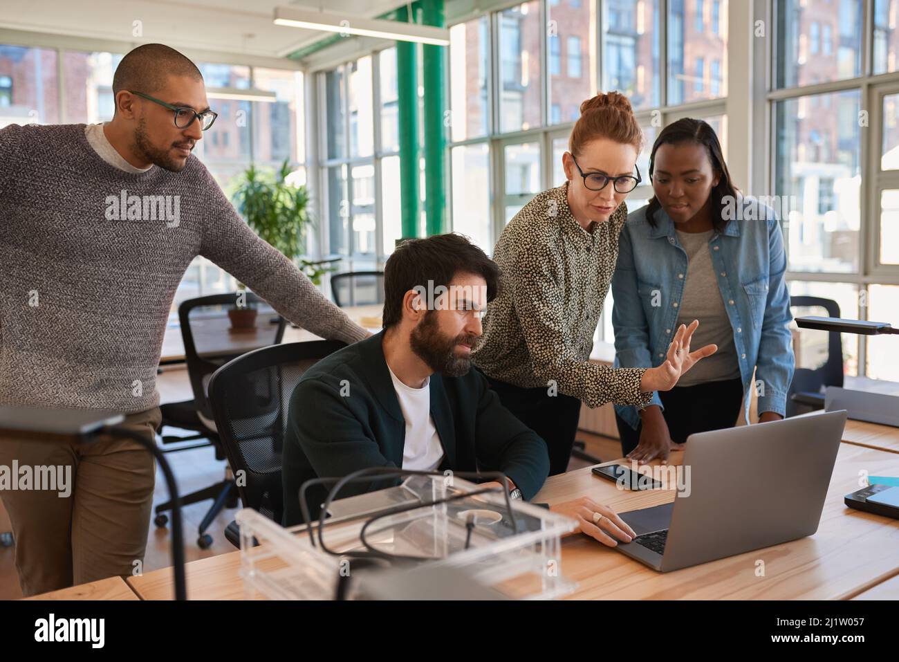 Konzentrierte Gruppe von verschiedenen Geschäftsleuten, die an einem Laptop zusammenarbeiten Stockfoto