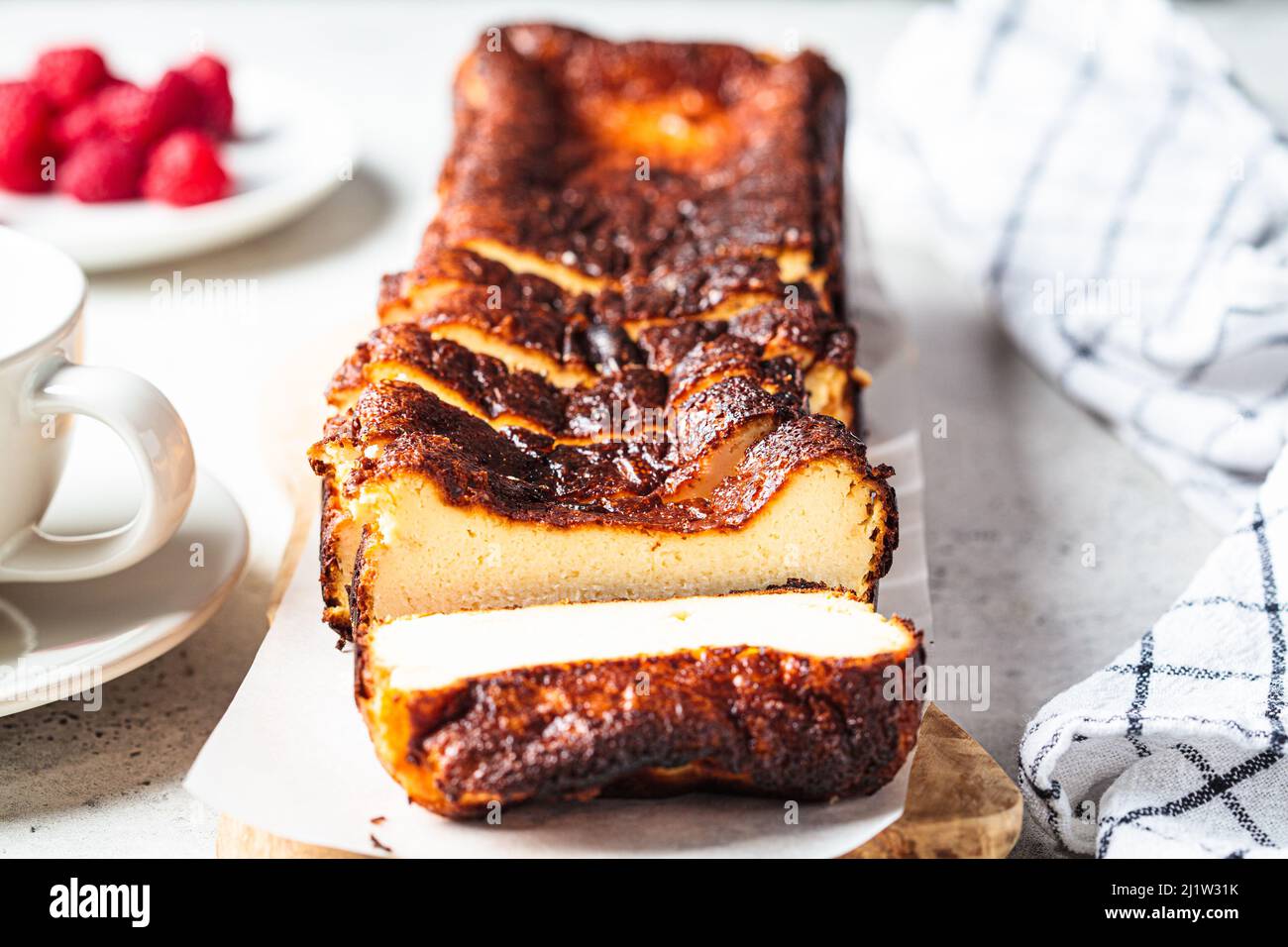 Hausgemachter rechteckiger San Sebastian verbrannte Käsekuchen auf Holzbrett zum Frühstück, Nahaufnahme. Stockfoto