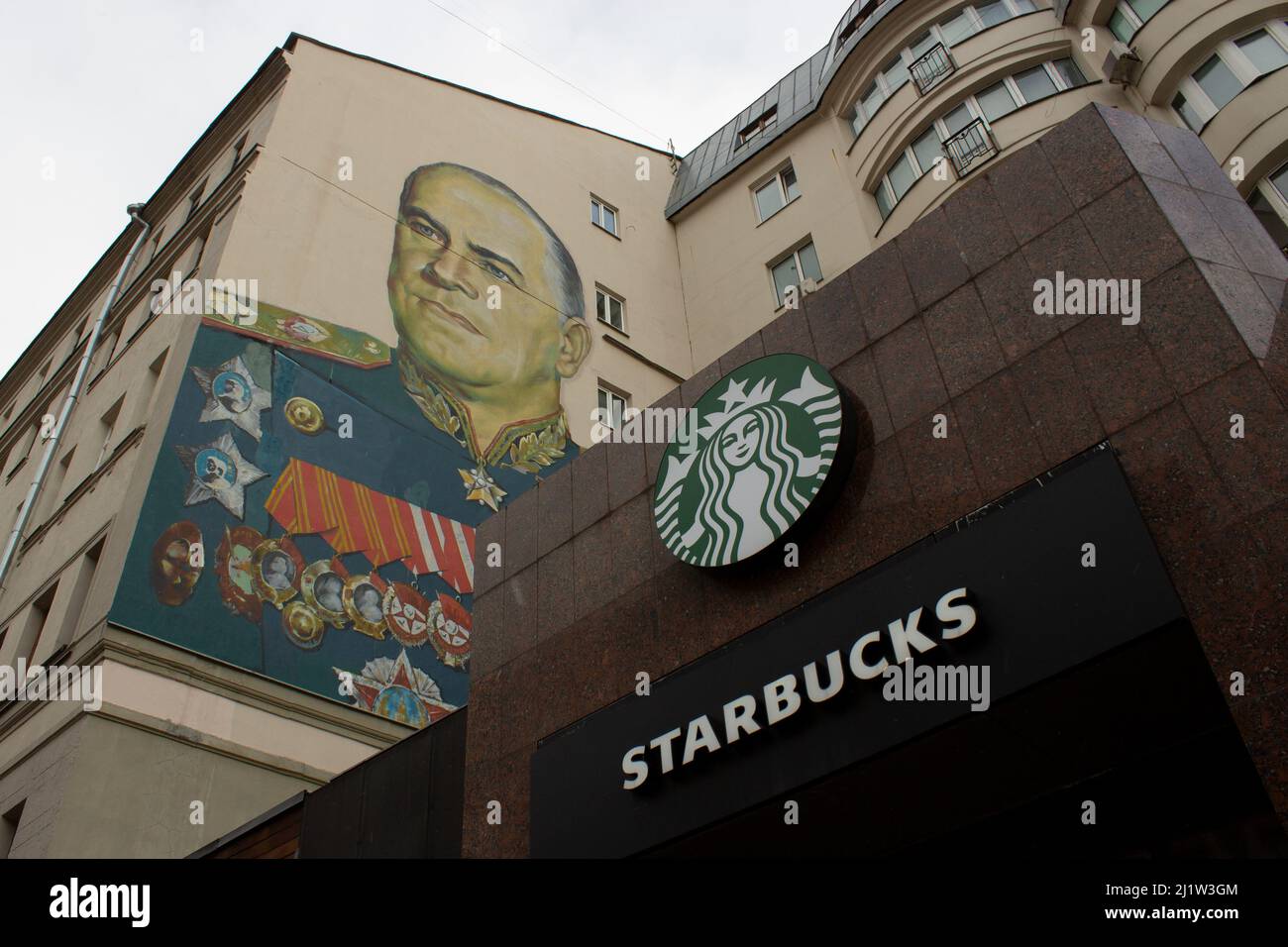 Moskau, Russland. 27. März 2022. Ein Starbucks-Schild ist neben dem Wandbild von Georgy Schukow zu sehen, einem sowjetischen General und Marschall der Sowjetunion, der einige der entscheidenden Siege der UdSSR über Nazi-Deutschland während des Zweiten Weltkriegs überwachte. Kredit: SOPA Images Limited/Alamy Live Nachrichten Stockfoto