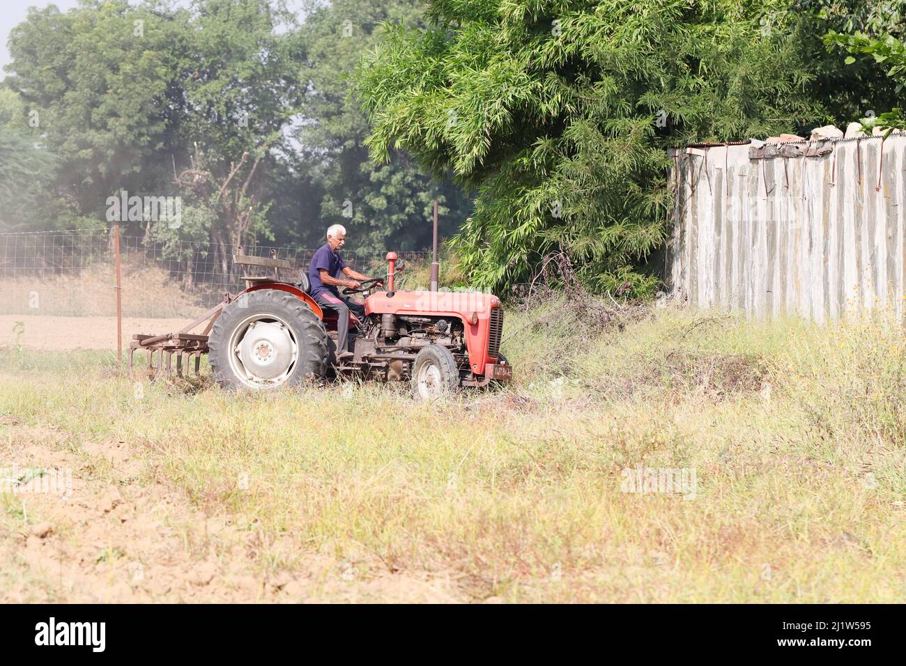 Pali Rajasthan, Indien. November 04 ,2021.Seitenansicht eines Bauern sitzt auf einem Traktor, der mit einem Pflug das Feld pflügt Stockfoto
