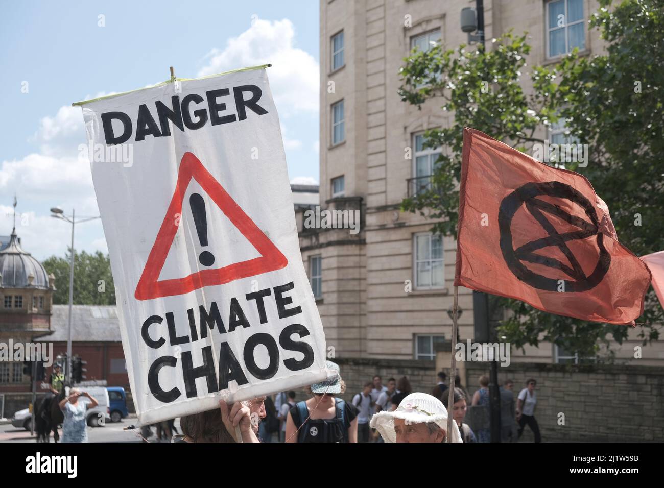 Plakat „Gefahr-Klima-Chaos“ und Aussterbungsflagge. protestmarsch gegen den Klimawandel, Bristol, England, Großbritannien. 16. Juli 2019. Stockfoto