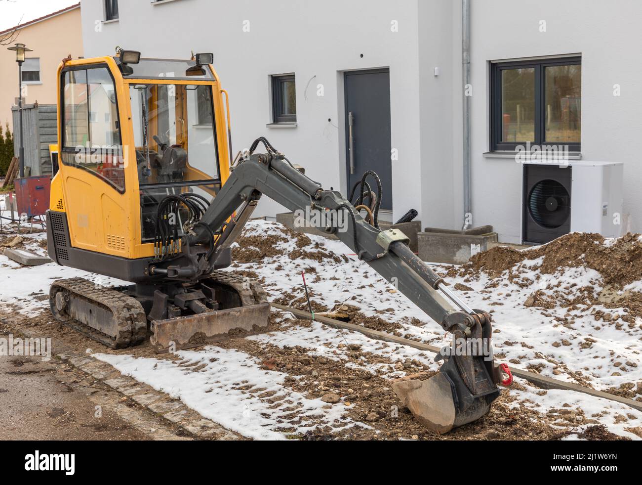 Kleiner Bagger, der vor einem neuen Gebäude abgestellt wurde Stockfoto