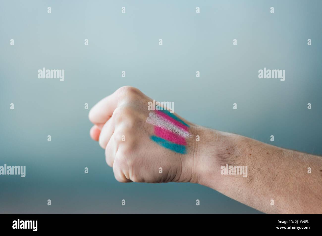 Eine anonyme Ernte mit farbenfrohen rosa und blauen Transgender-Streifen auf der Hand in hellem Raum Stockfoto