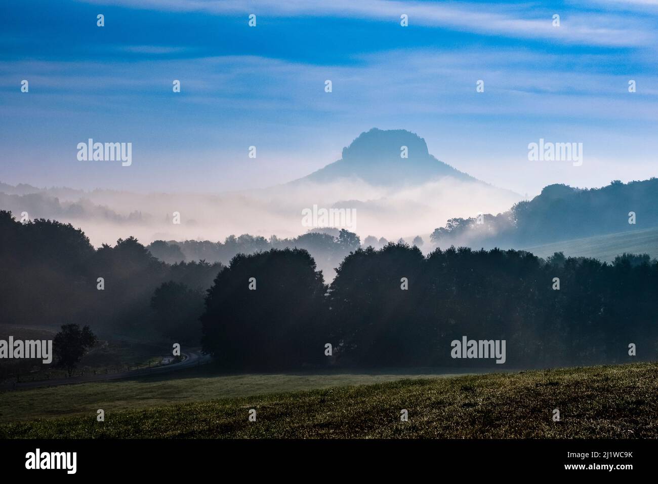 Landschaft mit Felsformationen und dem Gipfel Lilienstein im Nationalpark Sächsische Schweiz, das Elbtal bei Sonnenaufgang mit Nebel bedeckt. Stockfoto