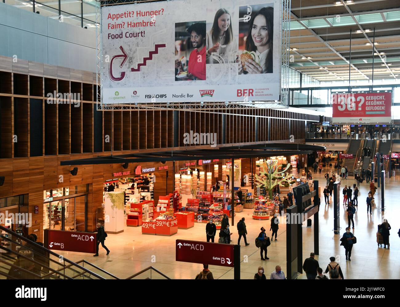 28. März 2022, Brandenburg, Schönefeld: Menschen laufen über den platz in der Haupthalle des Flughafens BER. Auf Flügen an die US-Ostküste müssen Berliner und Brandenburger nicht mehr unbedingt das Flugzeug wechseln. Ab Montag verbindet United Airlines Schönefeld täglich direkt mit dem New Yorker Flughafen Newark. Es ist die erste Fernverbindung vom BER in die USA. Foto: Bernd Settnik/dpa-Zentralbild/dpa Stockfoto
