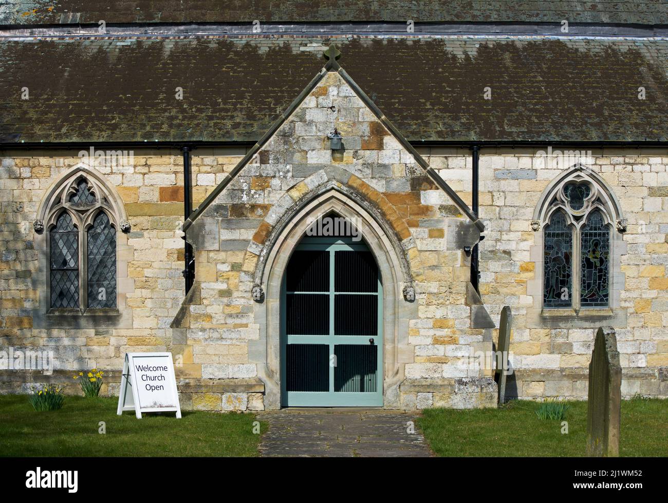 Schild - Willkommen, Kirche offen - vor der Tür der Allerheiligen Kirche im Dorf Hovingham im Bezirk Ryedale, North Yorkshire, England Stockfoto