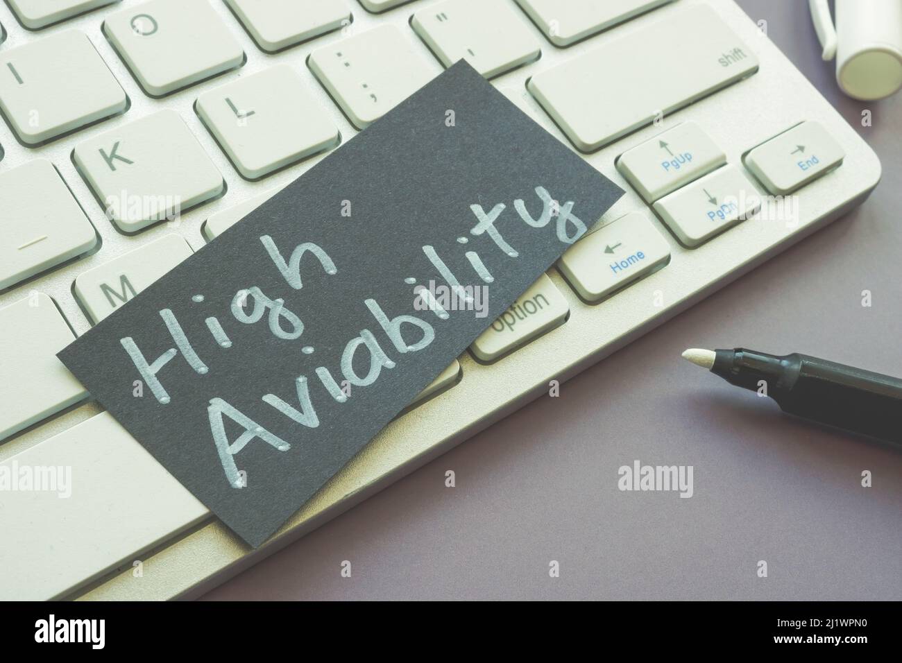 Auf der Tastatur liegt ein Blatt Papier mit Worten hoher Verfügbarkeit. Stockfoto