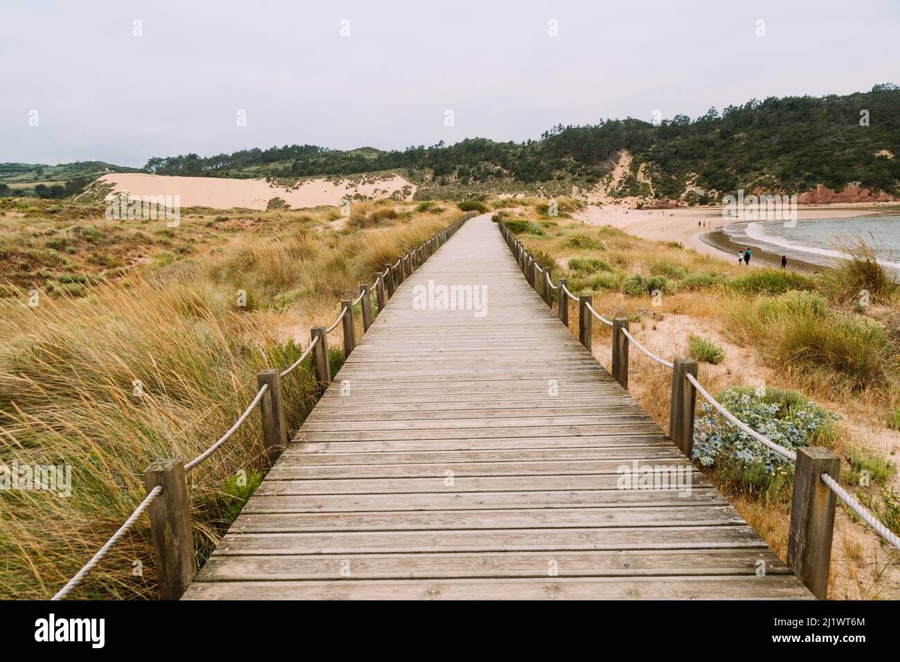 Holzsteg, der entlang der Bucht und dem Strand von Sao Martinhin do Porto verläuft, mit der Düne von Salir do Porto im Hintergrund Stockfoto