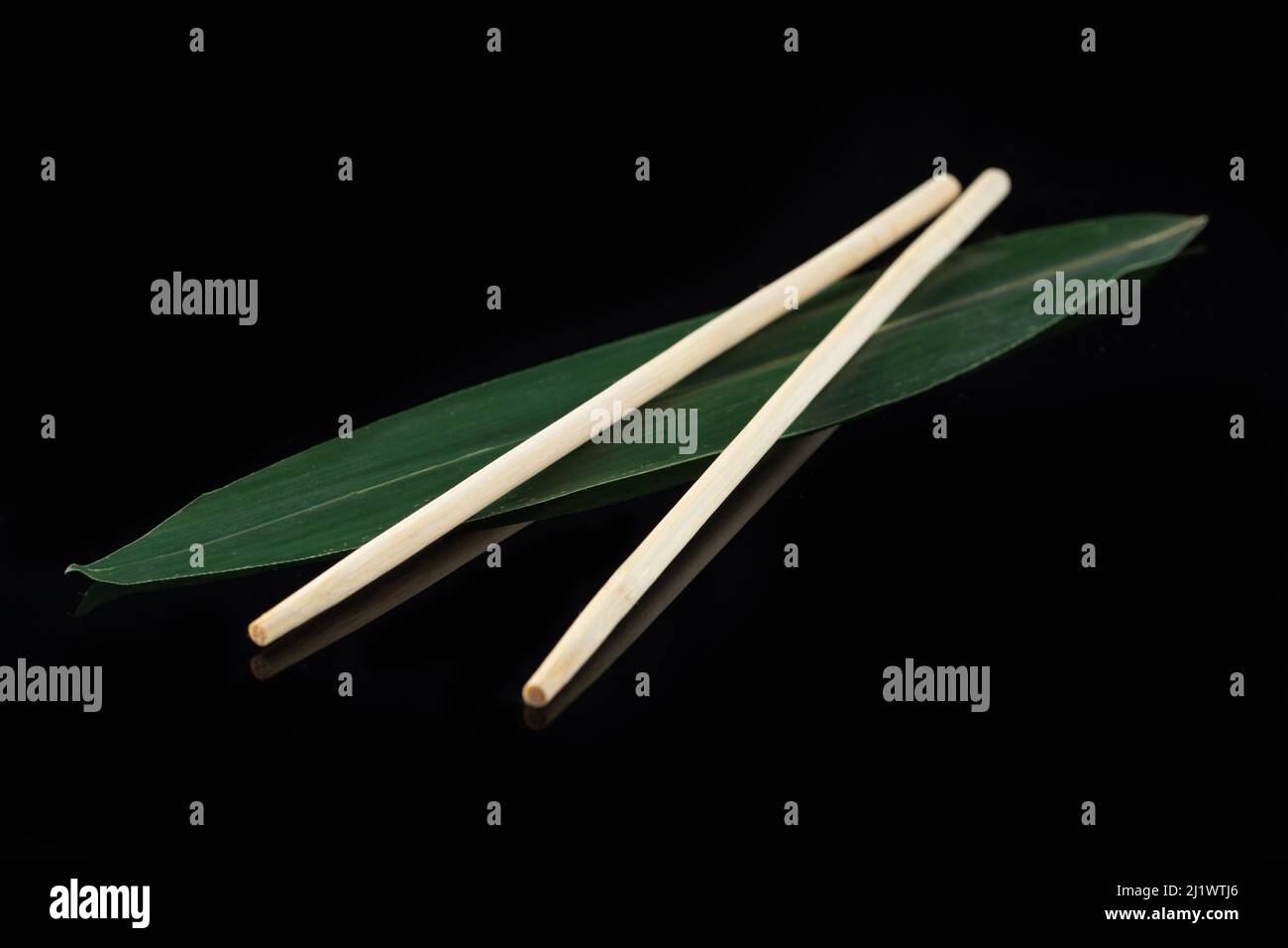 Sushi-Sticks auf einem Bananenblatt auf schwarzem Hintergrund mit Spiegelung. Sushi-Menü. Japanische Küche, Restaurant. Asiatische Küche Stockfoto