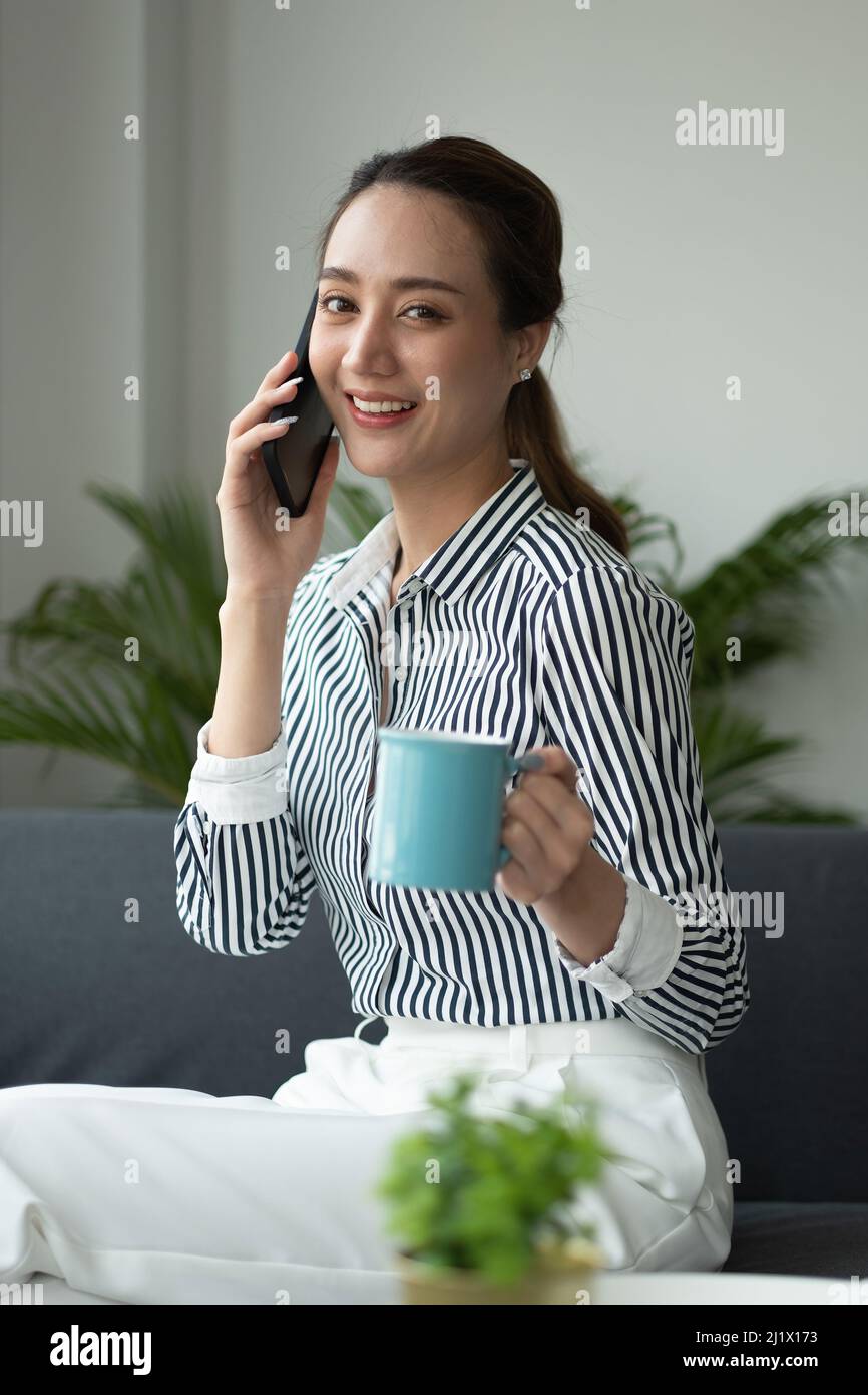 Attraktive asiatische Geschäftsfrau im Gespräch auf Handy mit Kunden. Stockfoto