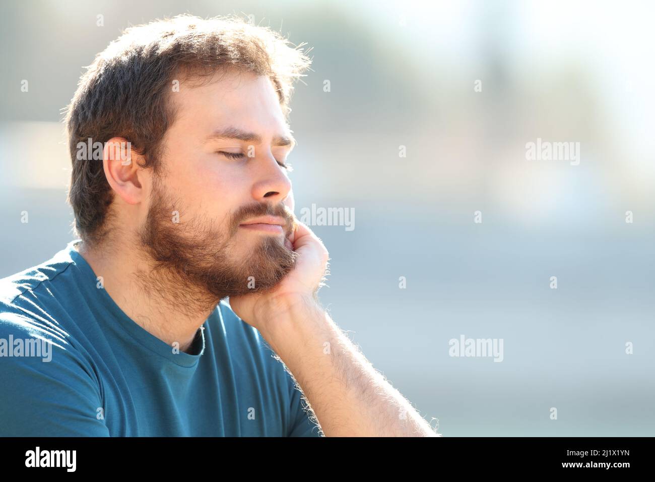 Entspannter Mann, der sich draußen mit geschlossenen Augen ausruhte, ein sonniger Tag Stockfoto